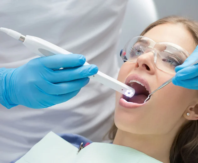 Dentist examining patient's teeth during routine dental checkup in clinical setting.
