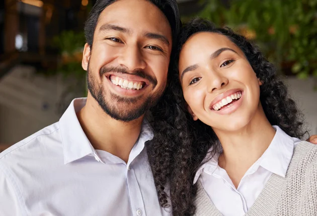Smiling couple posing together outdoors at evening, representing dental care and family wellness.